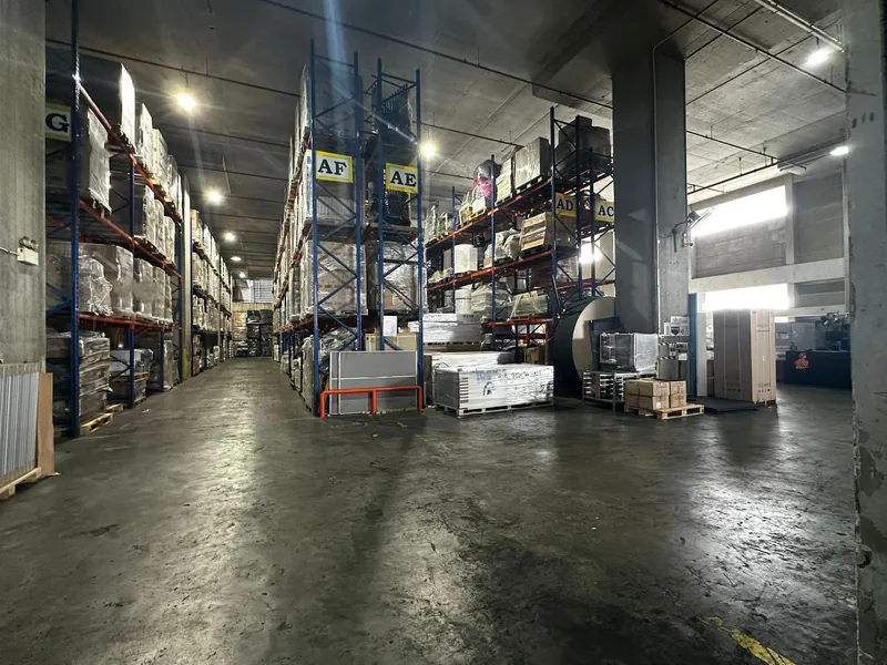 A storage aisle inside our warehouse, lined with tall blue and orange pallet racks holding wrapped, palletised cargo