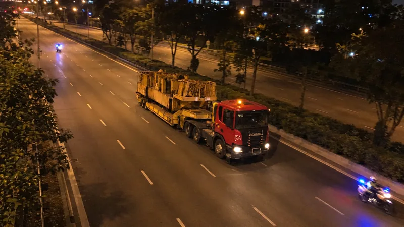 Illustration: a Hong Li prime mover moving oversized machinery at night under police escort